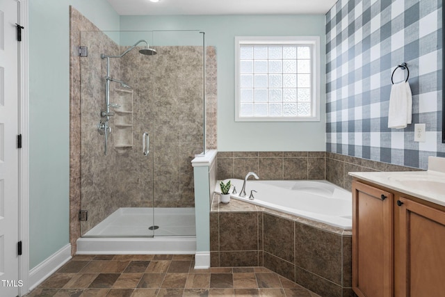 bathroom featuring a bath, a shower stall, vanity, baseboards, and wallpapered walls