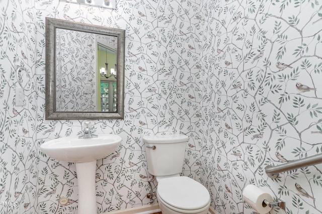 half bath with wallpapered walls and toilet