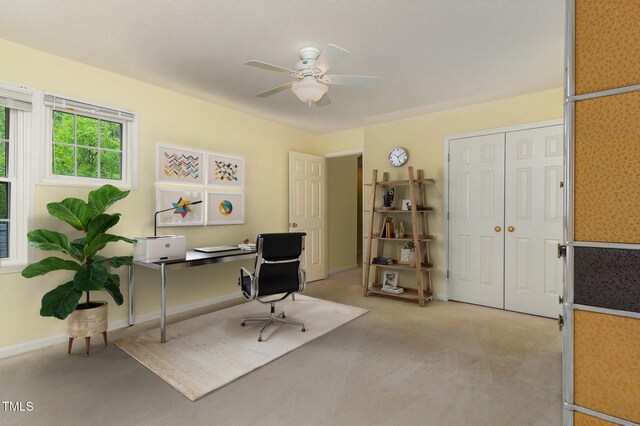 office featuring light carpet, a ceiling fan, and baseboards