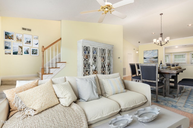 living area featuring stairway, baseboards, visible vents, and ceiling fan with notable chandelier