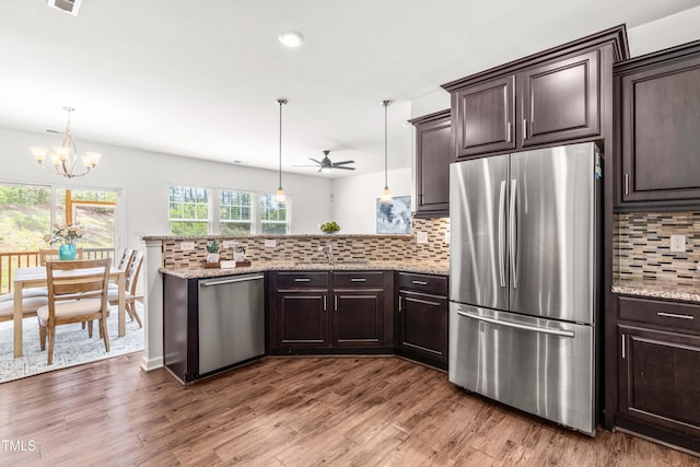 kitchen featuring appliances with stainless steel finishes, backsplash, a peninsula, and dark brown cabinets