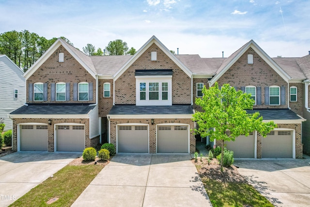 view of property with brick siding, driveway, and a garage