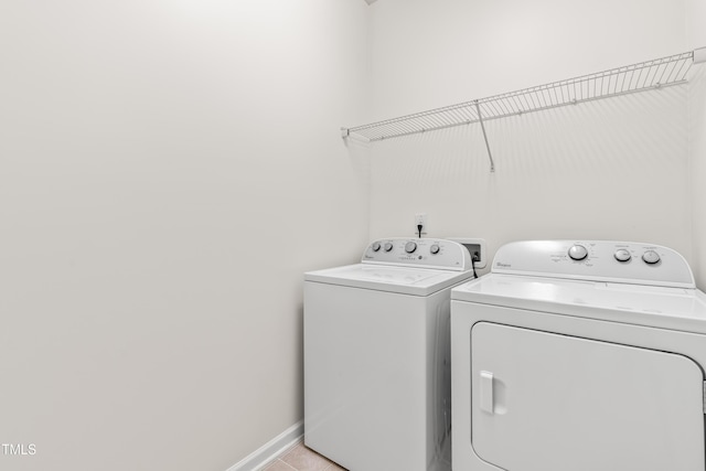 washroom with washer and dryer, light tile patterned floors, laundry area, and baseboards