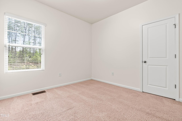 empty room featuring a healthy amount of sunlight, light carpet, and visible vents