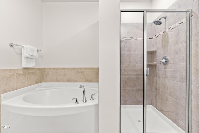 bathroom with a stall shower and a bath