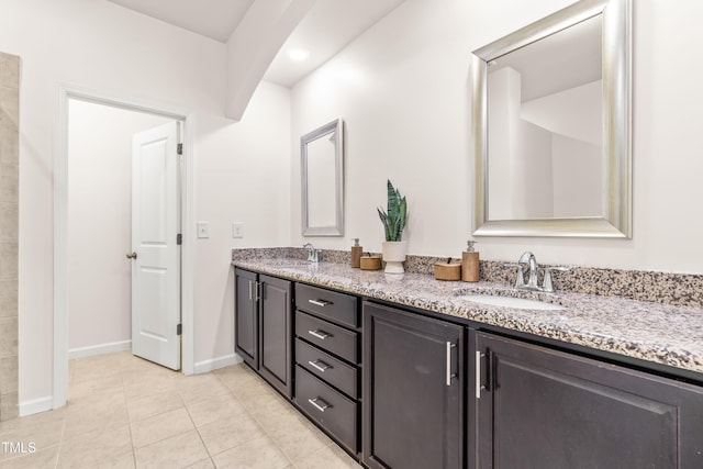 bathroom with a sink, baseboards, tile patterned flooring, and double vanity