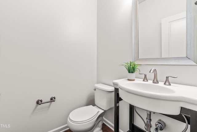 bathroom featuring toilet, baseboards, and wood finished floors