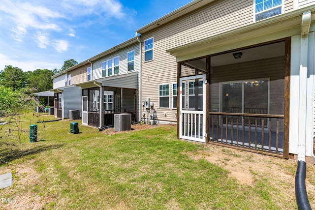 rear view of house with a lawn, central air condition unit, and a sunroom