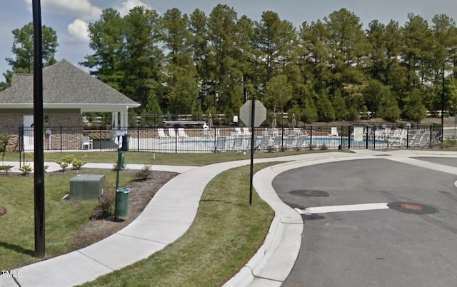 surrounding community with fence, a pool, and a lawn