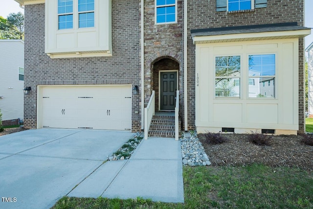 entrance to property with brick siding, an attached garage, stone siding, and driveway