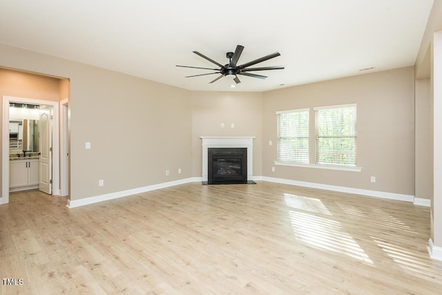 unfurnished living room featuring a fireplace with flush hearth, visible vents, light wood-type flooring, baseboards, and ceiling fan