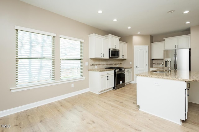 kitchen featuring light wood-style flooring, appliances with stainless steel finishes, decorative backsplash, and a sink