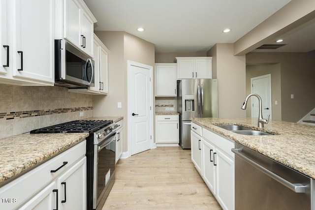 kitchen featuring white cabinetry, a sink, light wood-style floors, and appliances with stainless steel finishes