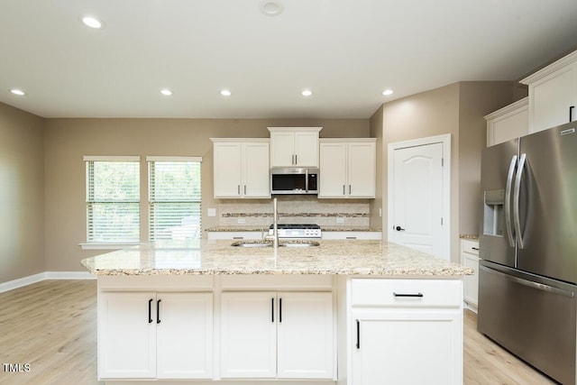 kitchen featuring white cabinetry, light stone countertops, stainless steel appliances, and light wood-style floors
