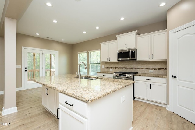 kitchen featuring light wood-style flooring, a sink, backsplash, and appliances with stainless steel finishes
