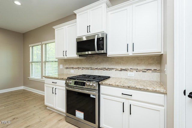 kitchen with stainless steel appliances, light wood-type flooring, baseboards, backsplash, and white cabinetry