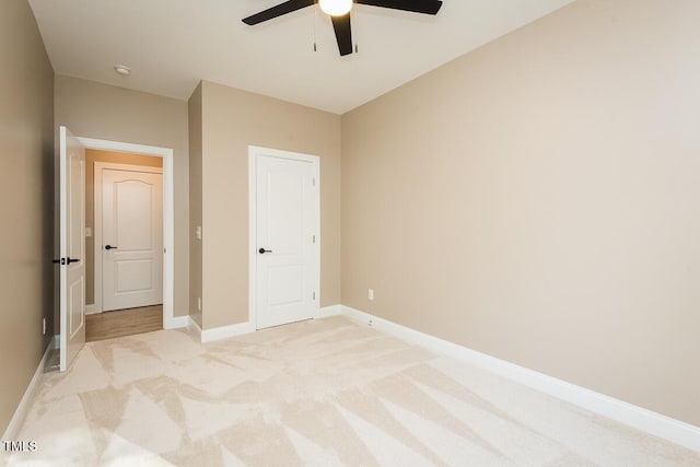 unfurnished bedroom featuring light carpet, a ceiling fan, and baseboards