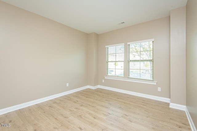spare room with baseboards, visible vents, and light wood finished floors