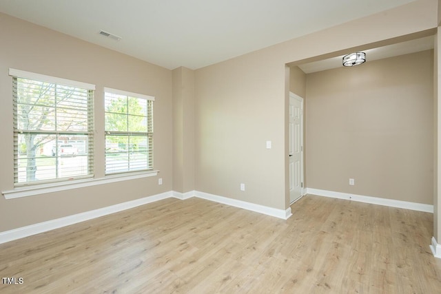 spare room with baseboards, light wood-style flooring, and visible vents