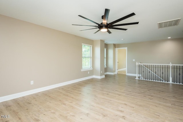 empty room featuring wood finished floors, visible vents, baseboards, and ceiling fan