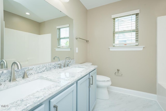 full bath with baseboards, toilet, a sink, and double vanity