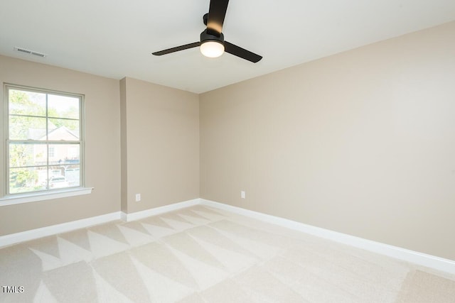 spare room with baseboards, a ceiling fan, visible vents, and light colored carpet