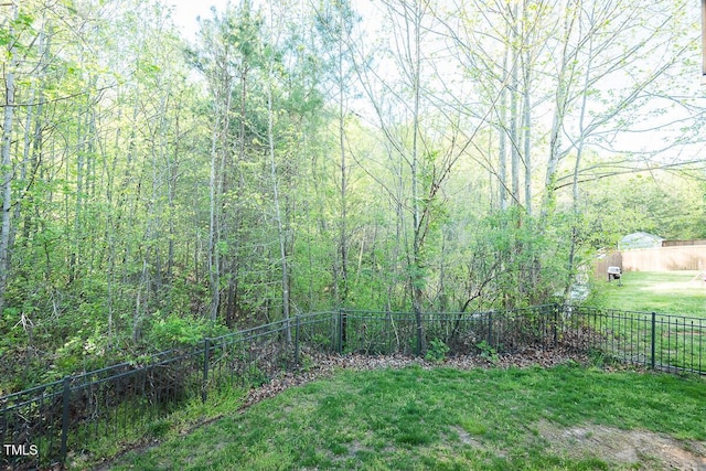 view of yard with a forest view and fence