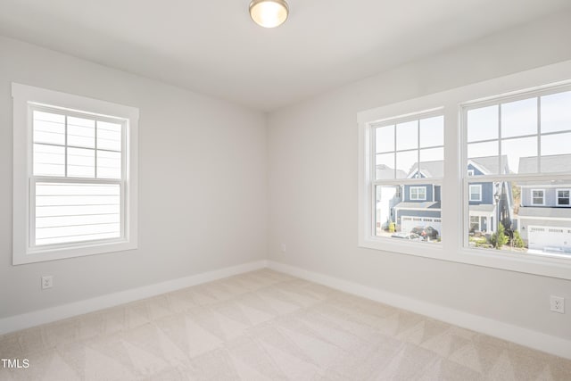 empty room featuring a wealth of natural light, baseboards, and carpet floors
