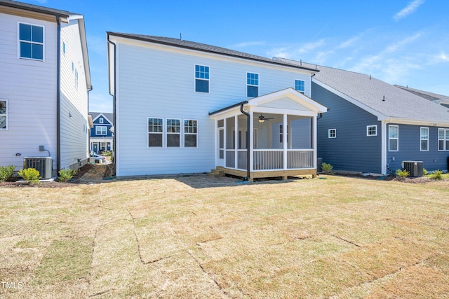 rear view of property featuring cooling unit, a lawn, a ceiling fan, and a sunroom