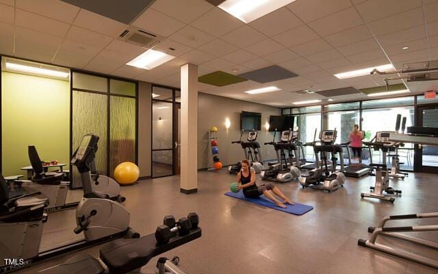 exercise room featuring expansive windows, a paneled ceiling, and visible vents