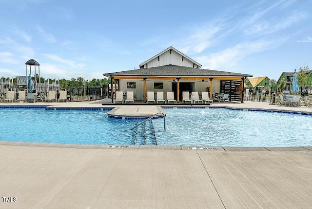 pool featuring a patio area, fence, and an outdoor structure