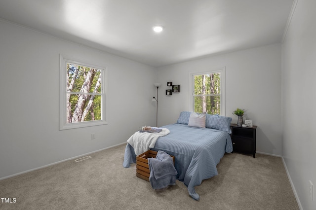 bedroom featuring baseboards, crown molding, visible vents, and carpet