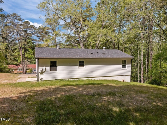rear view of house featuring roof with shingles and a yard