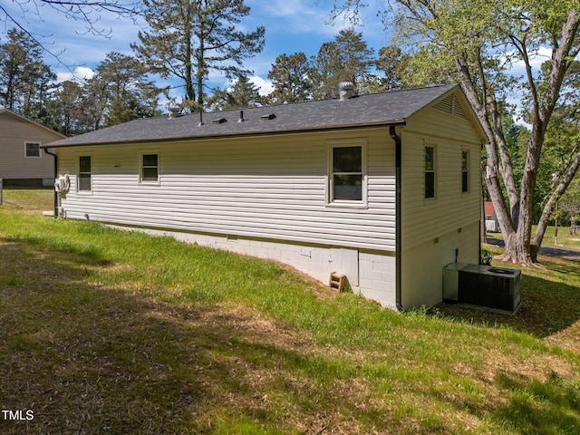 view of home's exterior featuring a lawn, central AC unit, and roof with shingles