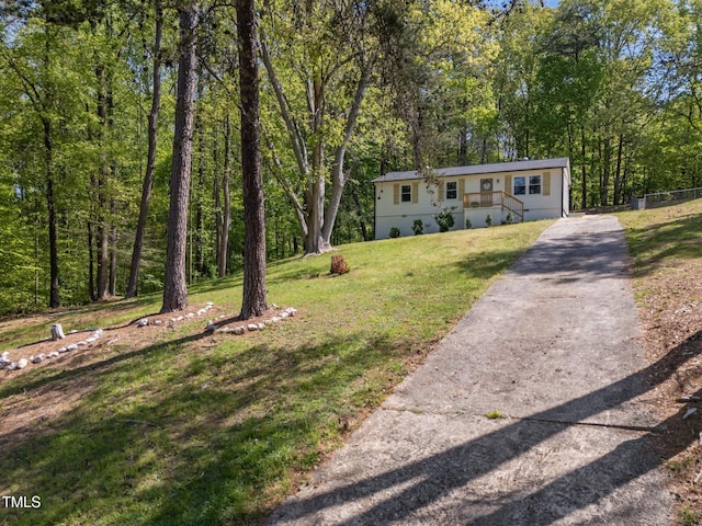 view of front of home with a forest view, a front lawn, and driveway