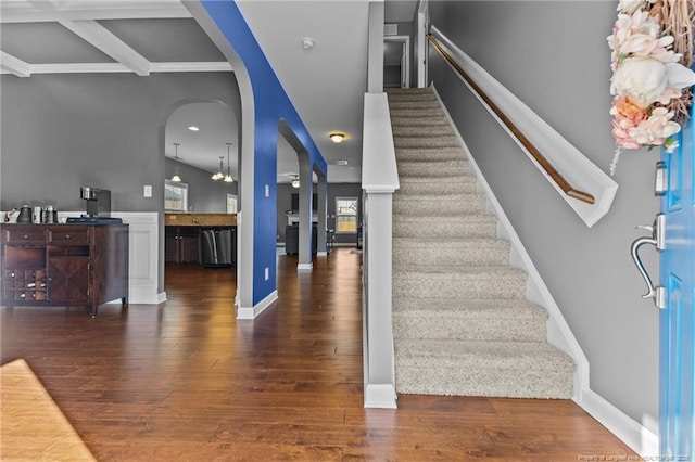 staircase with arched walkways and hardwood / wood-style floors