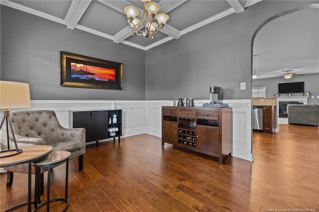 sitting room featuring ceiling fan with notable chandelier, beamed ceiling, a fireplace, coffered ceiling, and hardwood / wood-style flooring