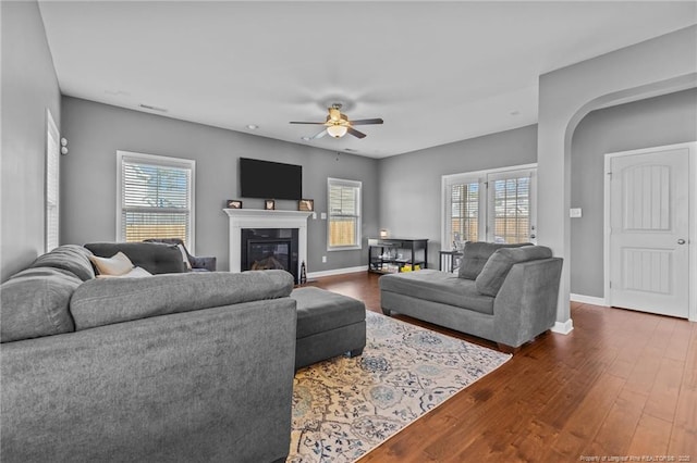 living area with wood finished floors, ceiling fan, baseboards, and a glass covered fireplace