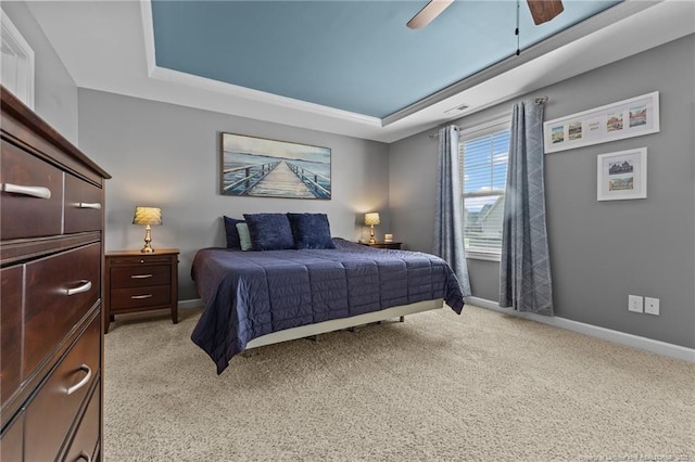 bedroom featuring baseboards, a raised ceiling, and light carpet