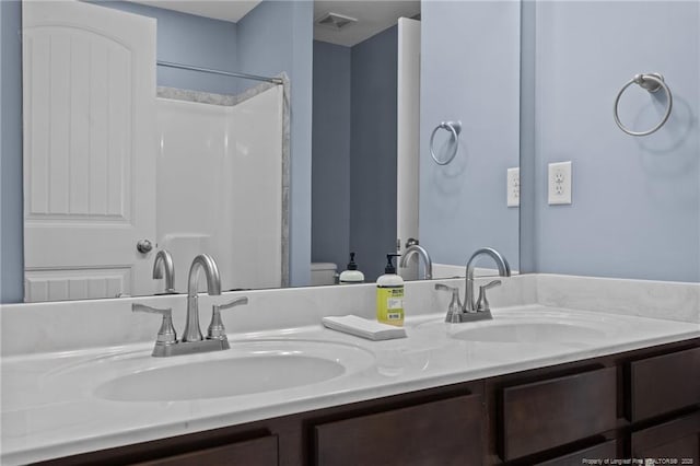 bathroom featuring double vanity, a sink, visible vents, and walk in shower