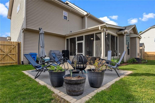 rear view of property featuring a patio, a gate, fence, a sunroom, and a lawn