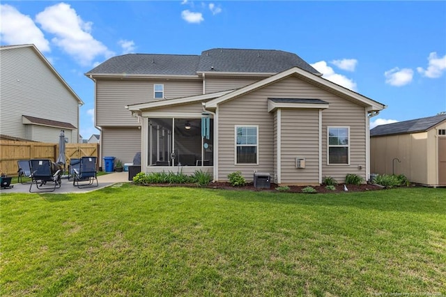 rear view of property featuring a patio area, central AC unit, a sunroom, fence, and a lawn