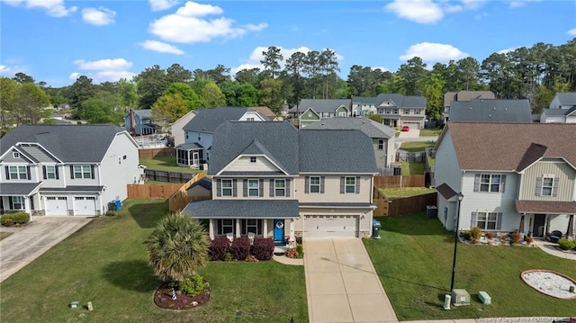 view of front of property featuring an attached garage, concrete driveway, fence, and a residential view