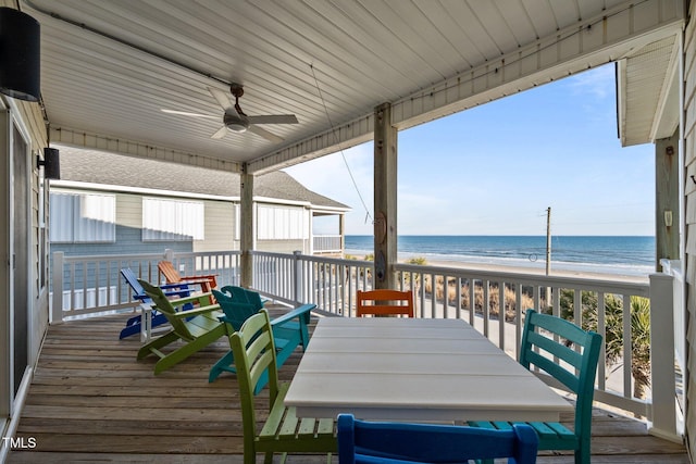 deck with a ceiling fan, a view of the beach, outdoor dining area, and a water view