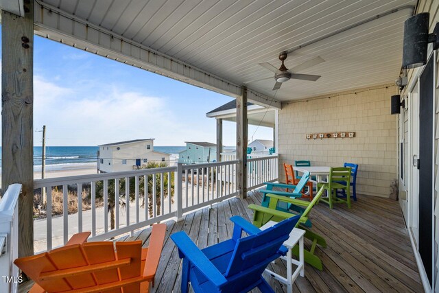 deck featuring a view of the beach, ceiling fan, and a water view