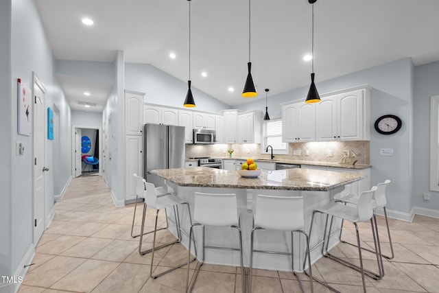 kitchen with light stone countertops, white cabinetry, a large island, stainless steel appliances, and decorative backsplash