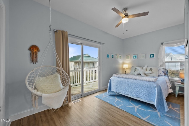 bedroom featuring access to exterior, wood finished floors, multiple windows, and visible vents