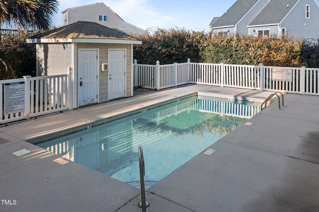 pool featuring an outbuilding, a storage shed, and a patio