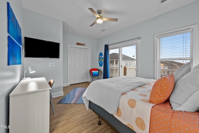 bedroom featuring a closet, baseboards, light wood-style flooring, a ceiling fan, and access to exterior