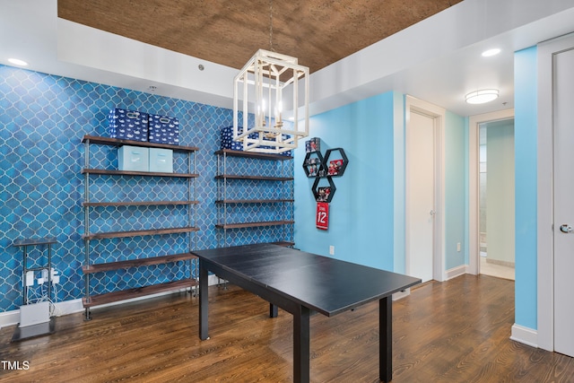 recreation room with baseboards, a chandelier, wood finished floors, and an accent wall